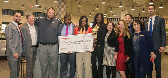 Several people standing to present oversized check for $72,000 to the Special Olympics